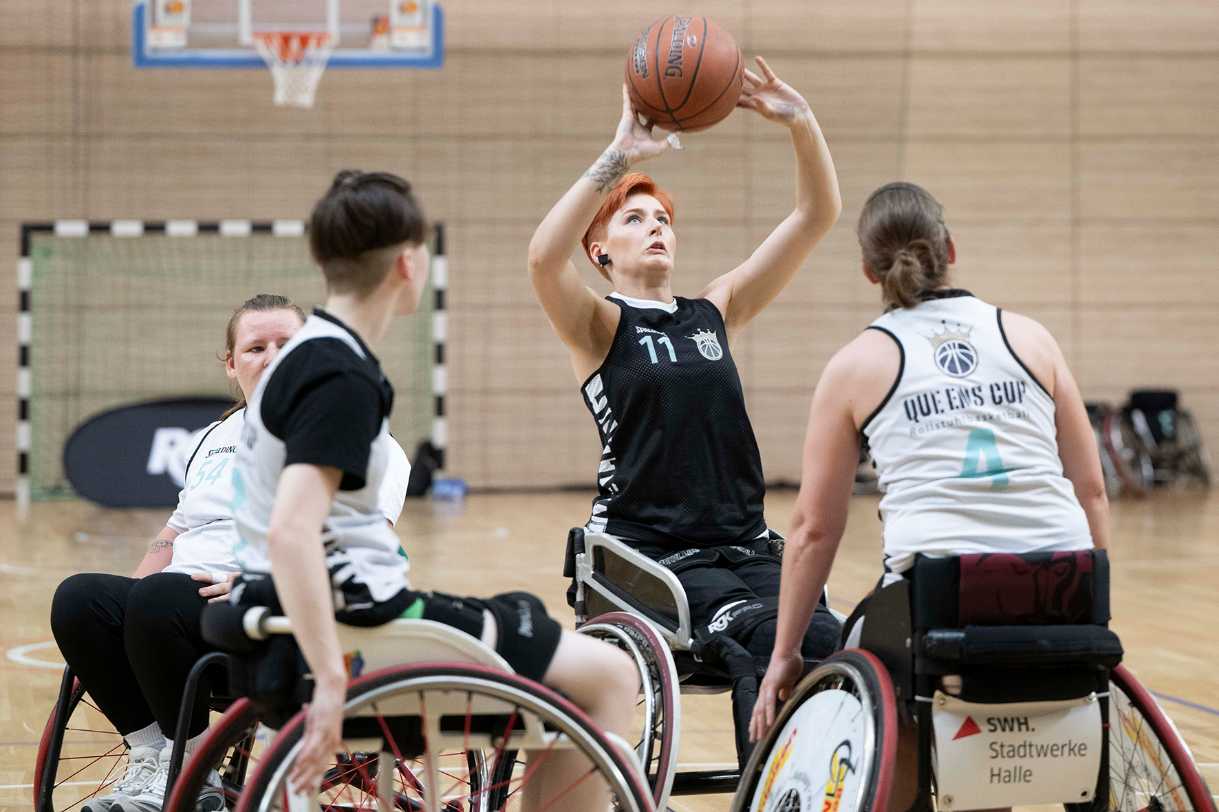 Junge Frau im Rollstuhl wirft auf einen Basketballkorb, umringt von zwei Gegenspielerinnen. | Foto: Volker Ballisch